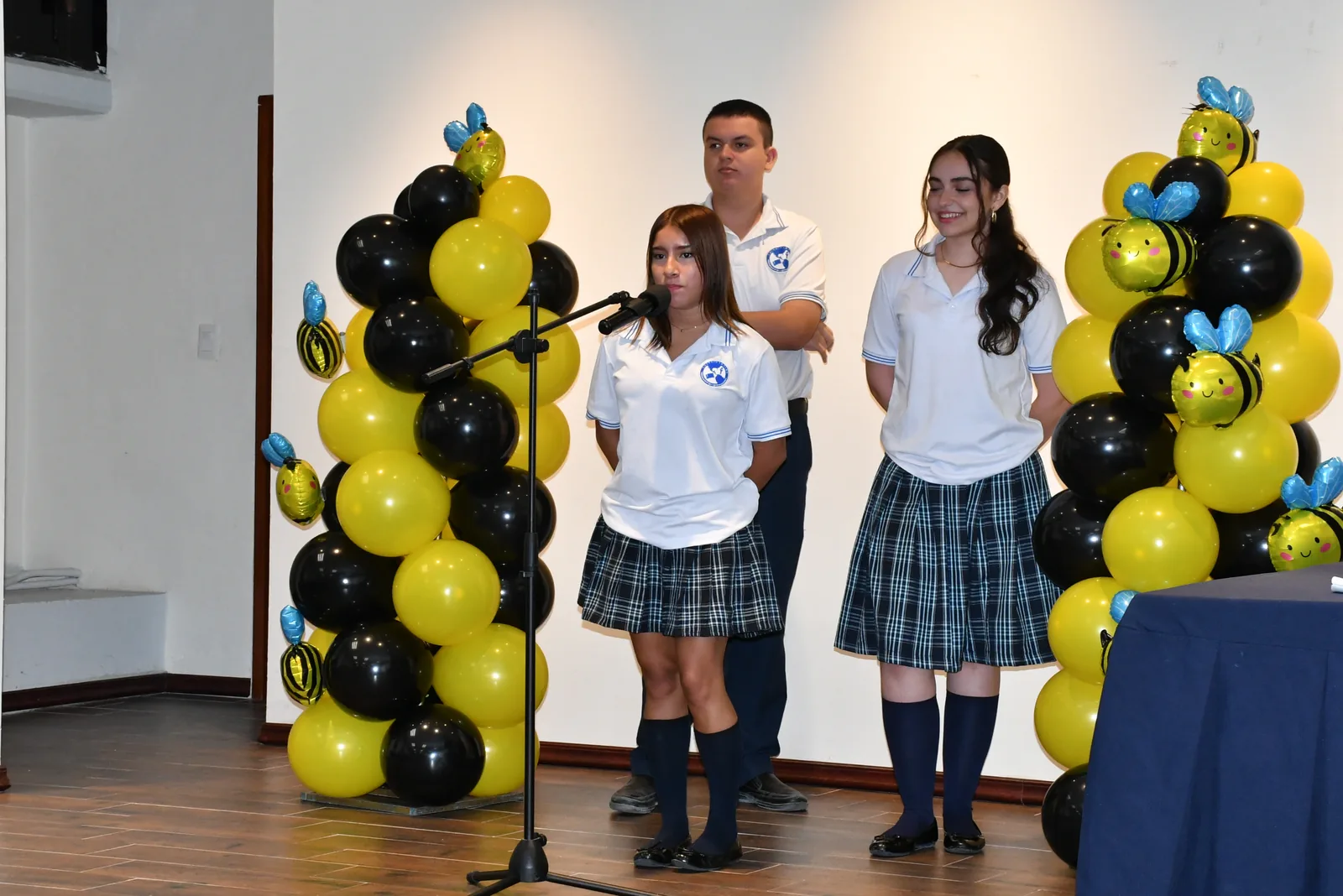 Estudiantes de Colegio Latino en el escenario del concurso Spelling Bee, decorado con globos temáticos de abejas