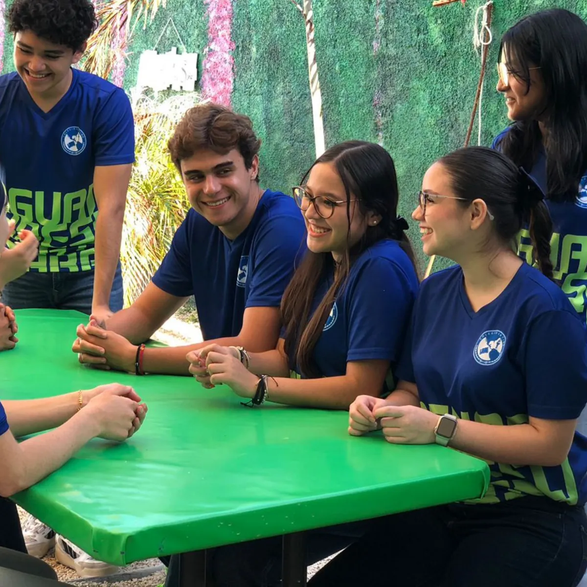 Estudiantes de Bachillerato de Colegio Latino conviviendo alrededor de una mesa en el patio escolar