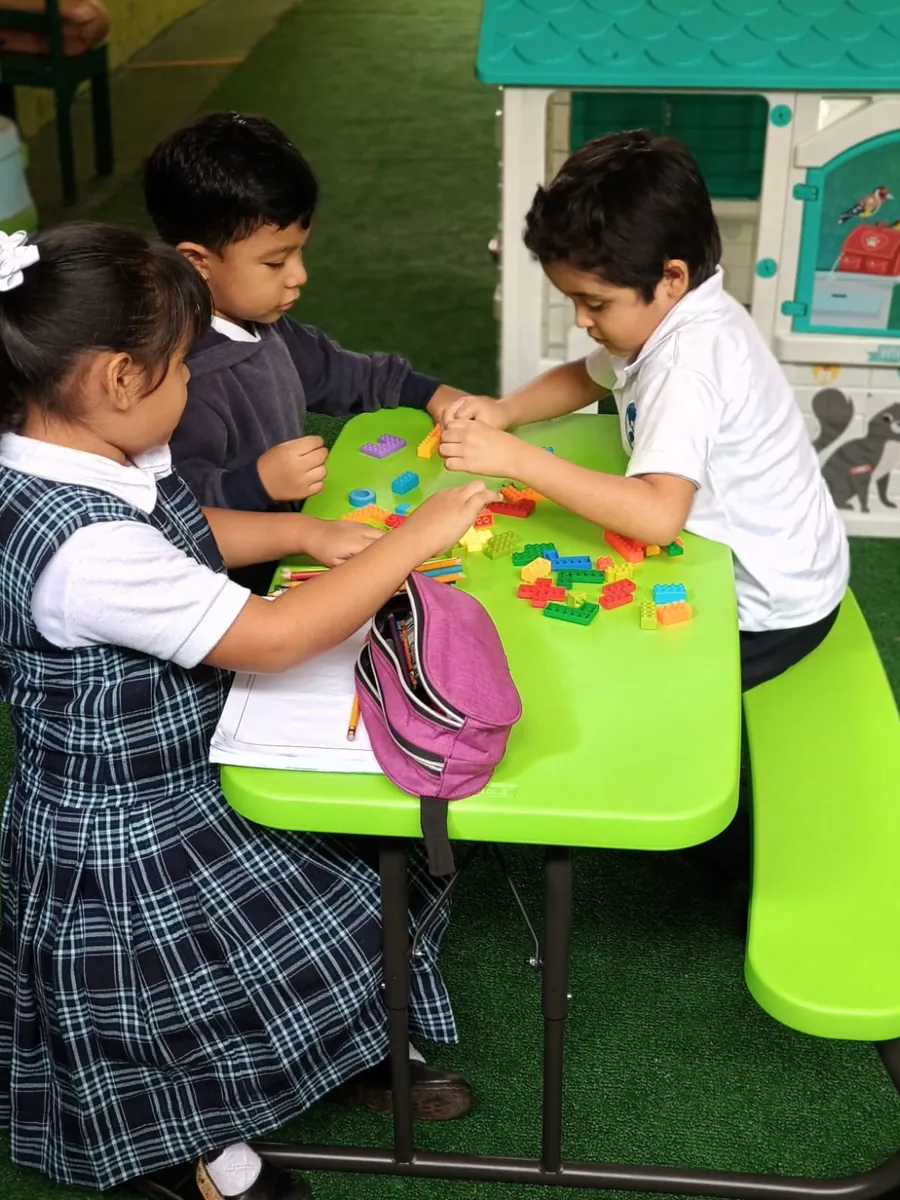 Estudiantes de Preescolar de Colegio Latino compartiendo materiales de trabajo en equipo dentro del aula