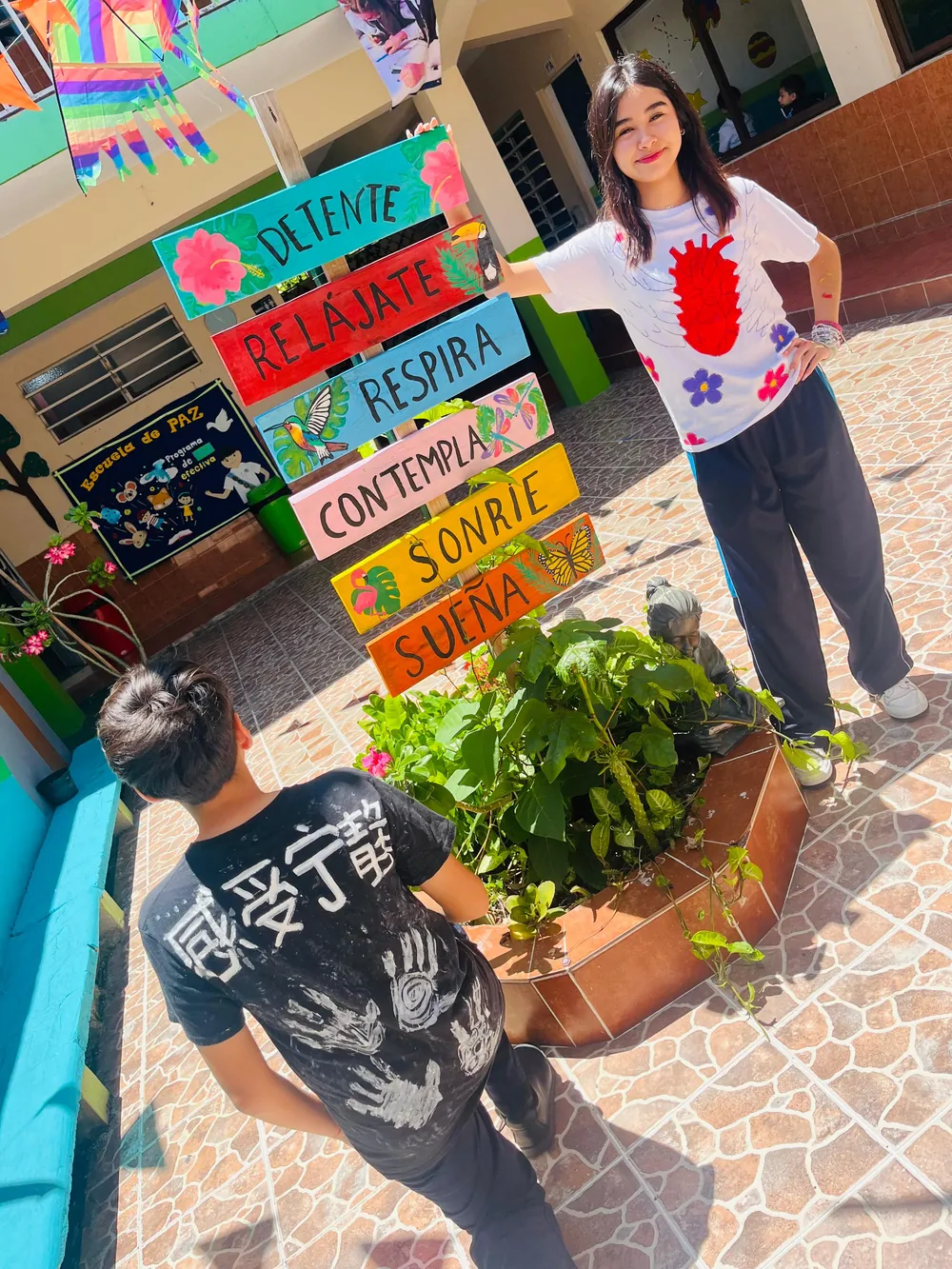 Estudiantes de Secundaria de Colegio Latino junto a un letrero del Programa de Paz con mensajes de bienestar emocional